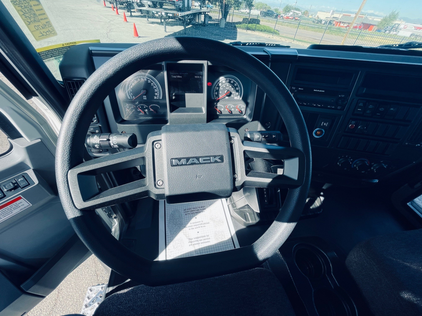 Steering wheel and dashboard of a new 2026 Mack MD6 truck showing Mack emblem on the center, gauge cluster, and control panels.