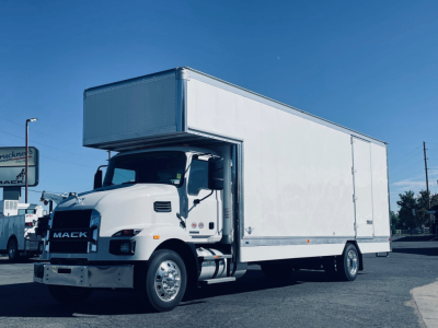 Box truck with raised sleeper cab, Mack MD6 front, white cargo box, view of driver's side, VIN 1M2MDBAA1TS018827 text not visible on image.