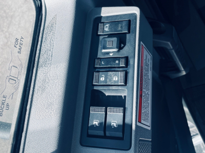 Dashboard switch panel with window controls and lock switches in a Mack MD6 cab, plus safety label edge visible.
