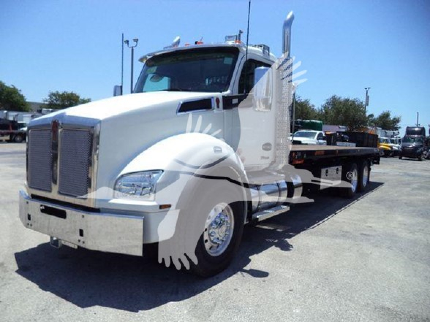 Kenworth T880 rollback truck in a parking lot, white; side view showing cab, chrome grille, large fuel tanks, dual rear wheels, and flatbed with wheel lift.