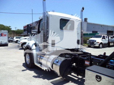 Kenworth T880 cab with a large fuel tank, chrome exhaust stacks visible; side view shows cabin and chassis rails. No legible labels or serials readable in this view.