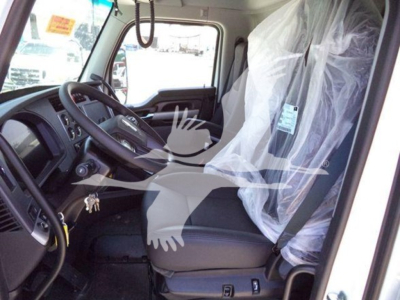 Kenworth T880 truck interior cab view showing steering wheel and driver's seat with plastic seat cover in a new vehicle.