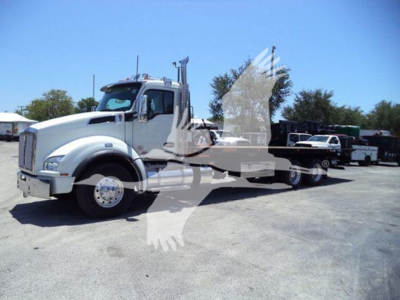 Kenworth T880 rollback truck in a parking lot with a long flatbed and white cab, side profile visible.