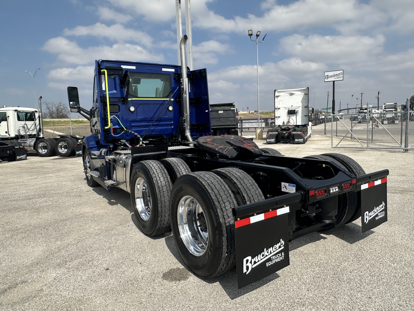 Volvo VNR truck chassis with three rear axles and mud flaps showing Goodyear tires and chrome wheels.