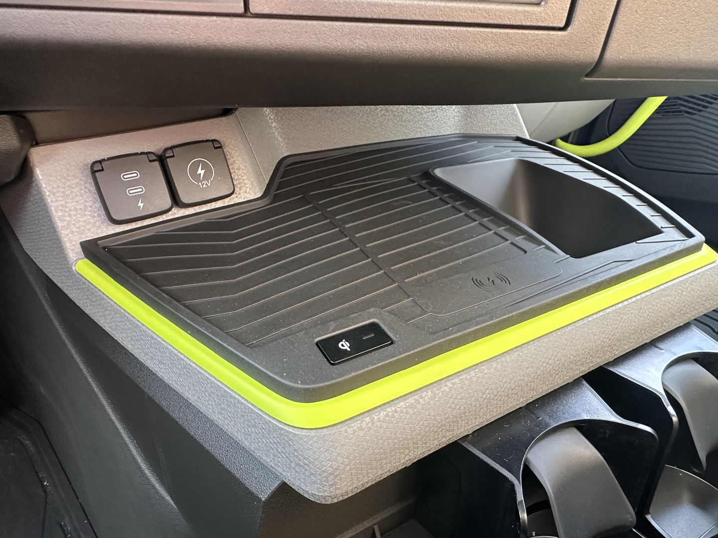 Volvo VNR64T300 dash area showing wireless charging pad and cup holder with surrounding lime-yellow accent trim.