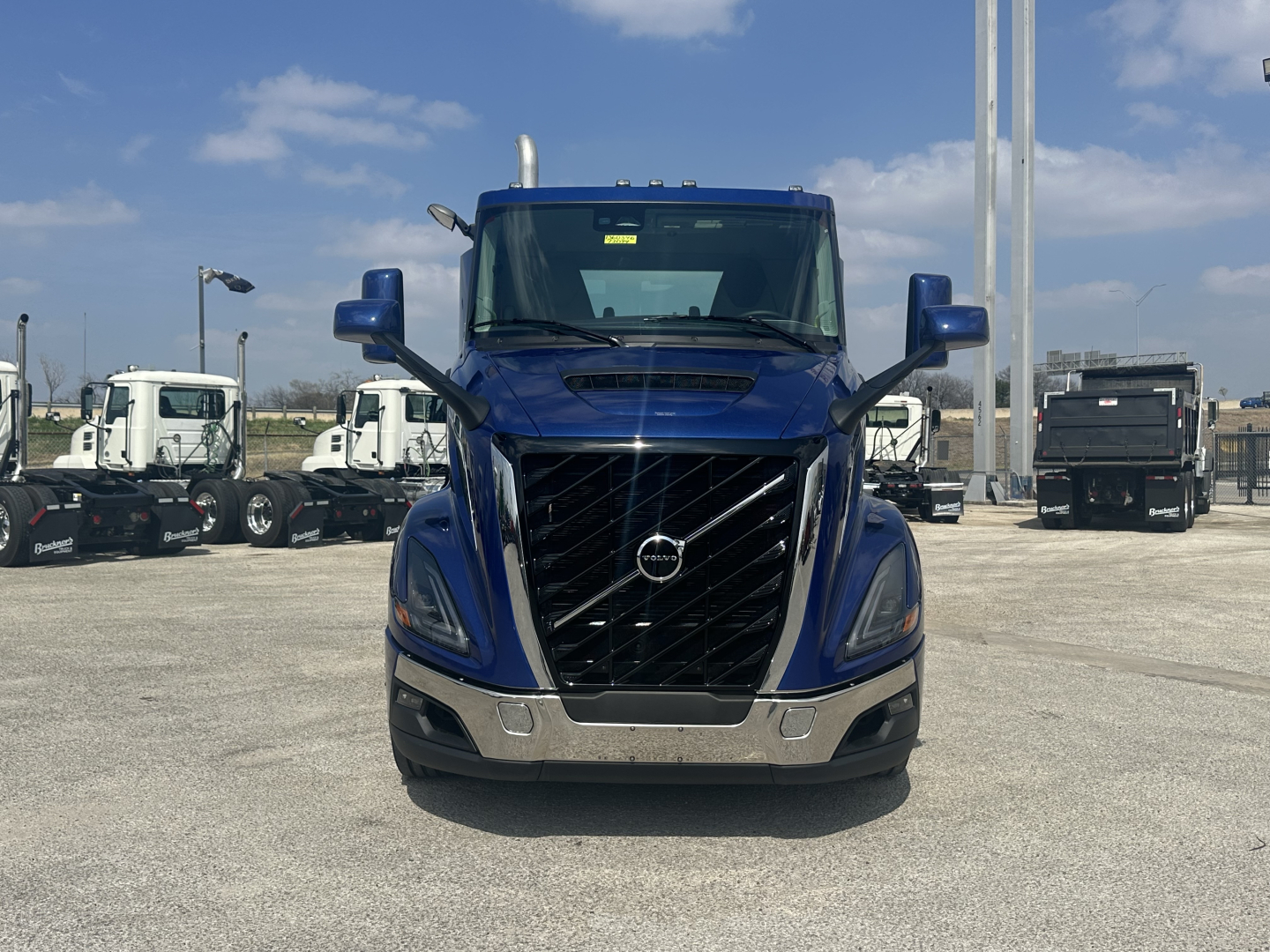 Volvo VNR64T300 cab-front view showing bold black grille, chrome bumper, blue exterior, large side mirrors, and Volvo emblem.