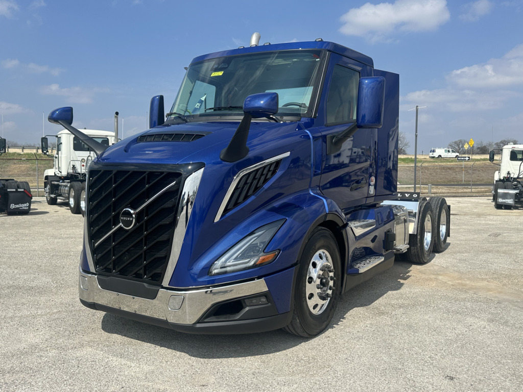 Blue Volvo VNR64T300 cab+chassis tractor in a lot, front grille with Volvo emblem, large headlights, chrome bumper, side mirrors, and dual rear axles.