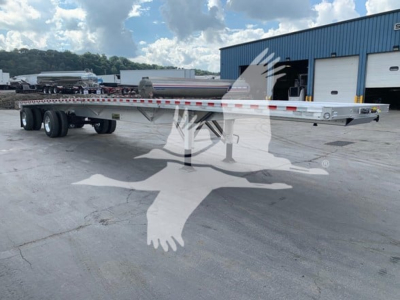 Flatbed trailer showing RK-100 style deck with dual rear axles, silver frame, and reflective tape along the rails.