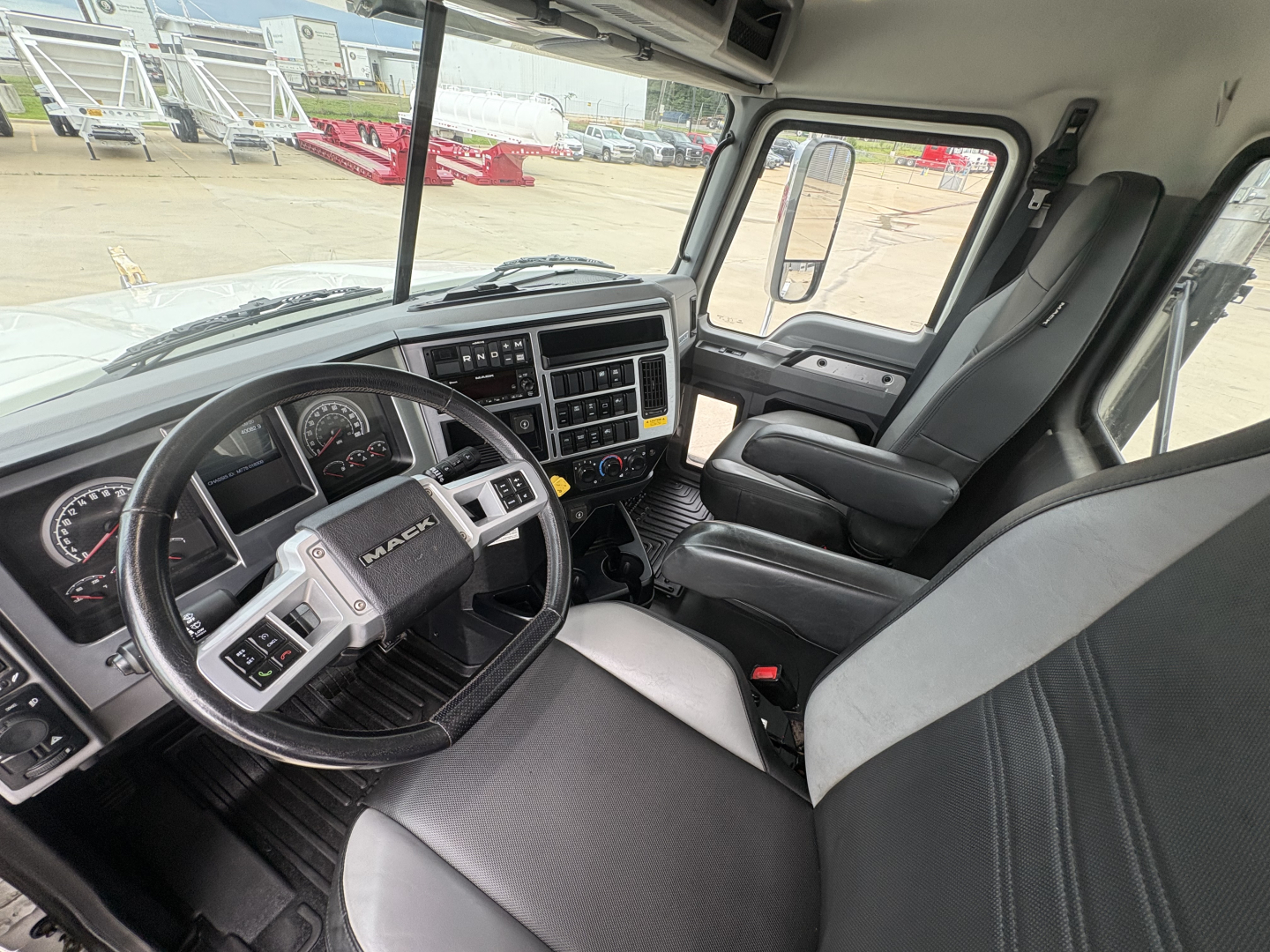 Interior cab view of a new 2026 Mack PI64T conventional daycab showing steering wheel, dashboard, and front seats.