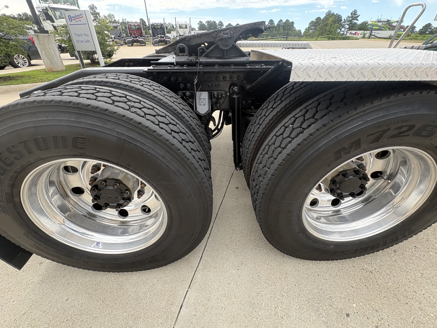 Mack PI64T truck chassis showing dual rear wheels and air tanks with polished chrome rims and tire branding visible.
