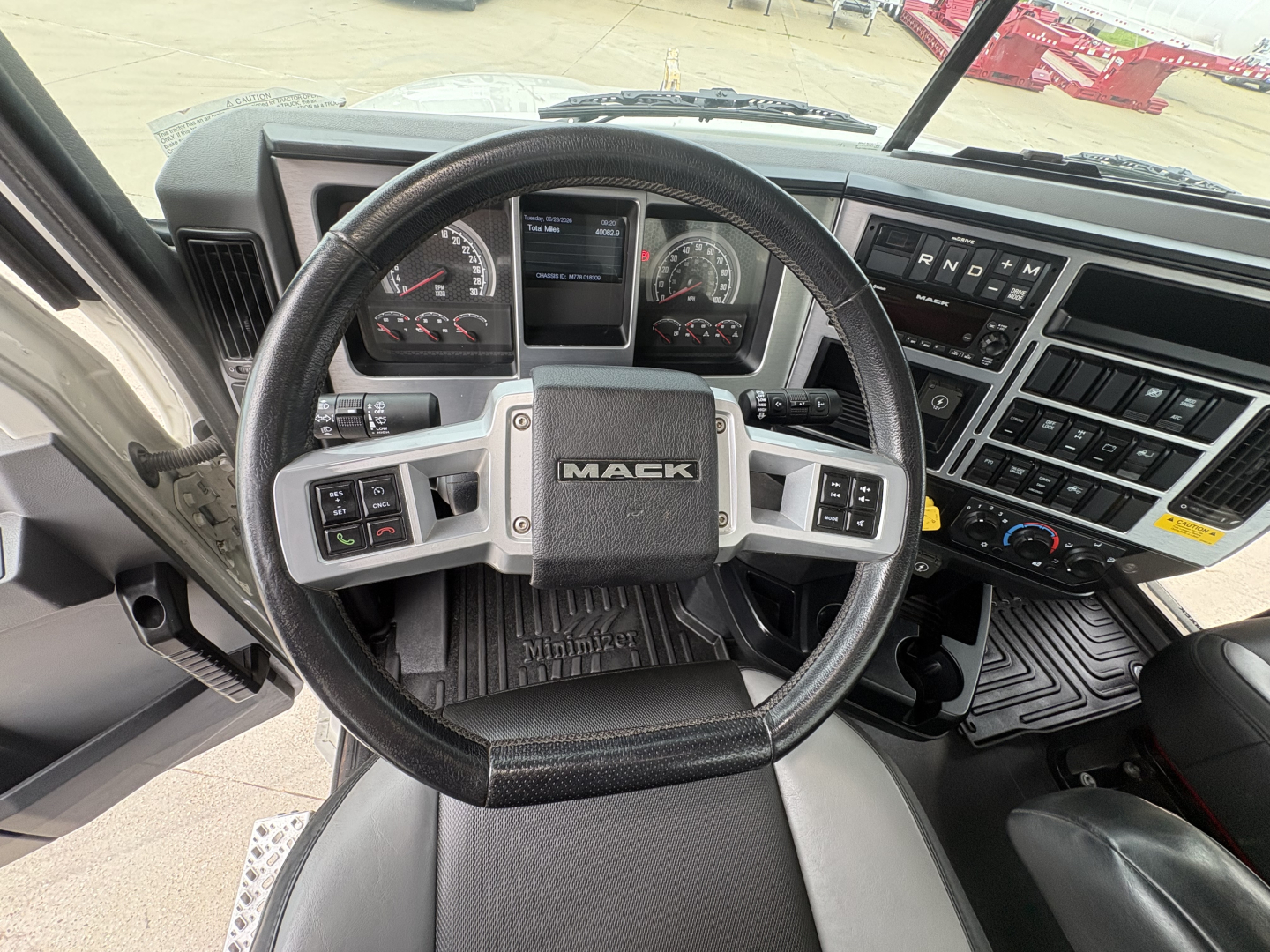 Mack PI64T truck interior showing steering wheel with Mack logo, dashboard gauges, and center console controls.
