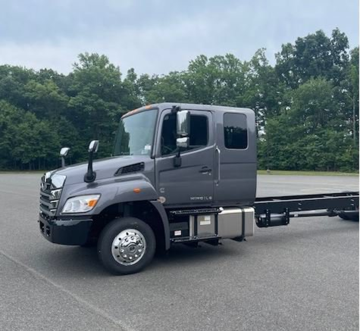 Hino L6 cab chassis truck in a parking lot showing the tractor cabin and side fuel tanks with wheels and chassis extending rearward