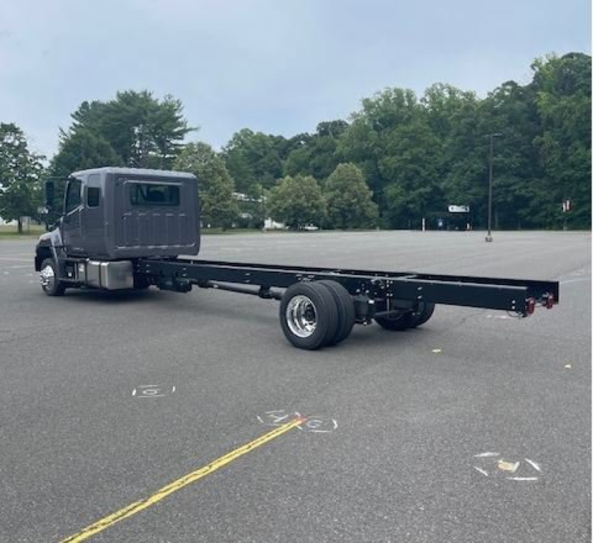 Cab chassis truck with a long flatbed frame and dual rear wheels, dark gray cab, Hino L6 model