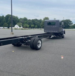 Hino cab chassis truck viewed from rear-left with long wheelbase and exposed frame; single rear axle; cab in dark color.