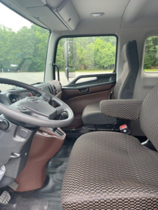Cab interior of a 2027 Hino L6 truck showing driver's seat, steering wheel, and front passenger seat with patterned upholstery.
