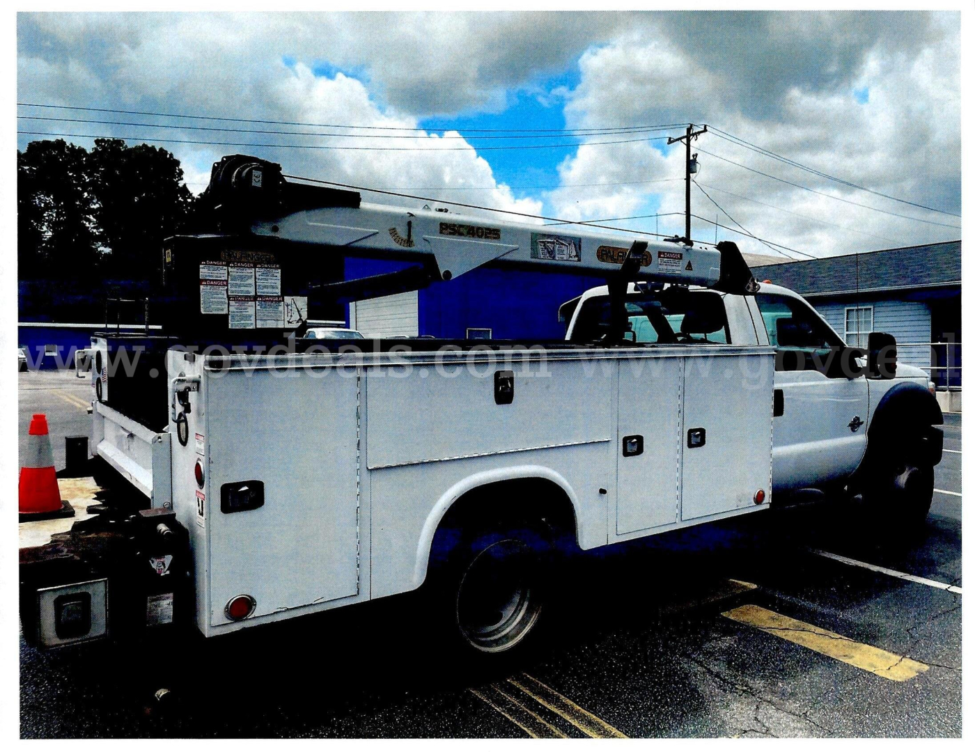 Ford F-450 service/utility truck with utility bed and crane, side view showing storage compartments and rack, used 2016 model.