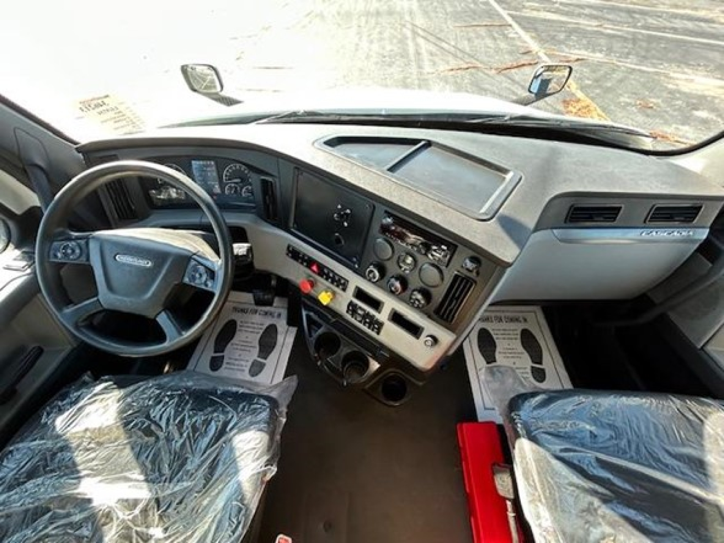 Cab interior of a Freightliner Cascadia 126 truck showing steering wheel, dashboard, and control panel with switches and vents.