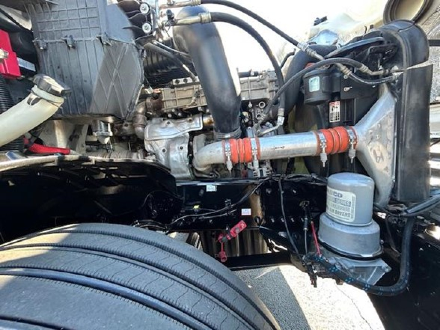 Freightliner Cascadia 126 engine bay showing front axle area, hoses, coolant reservoir, and air intake housing.