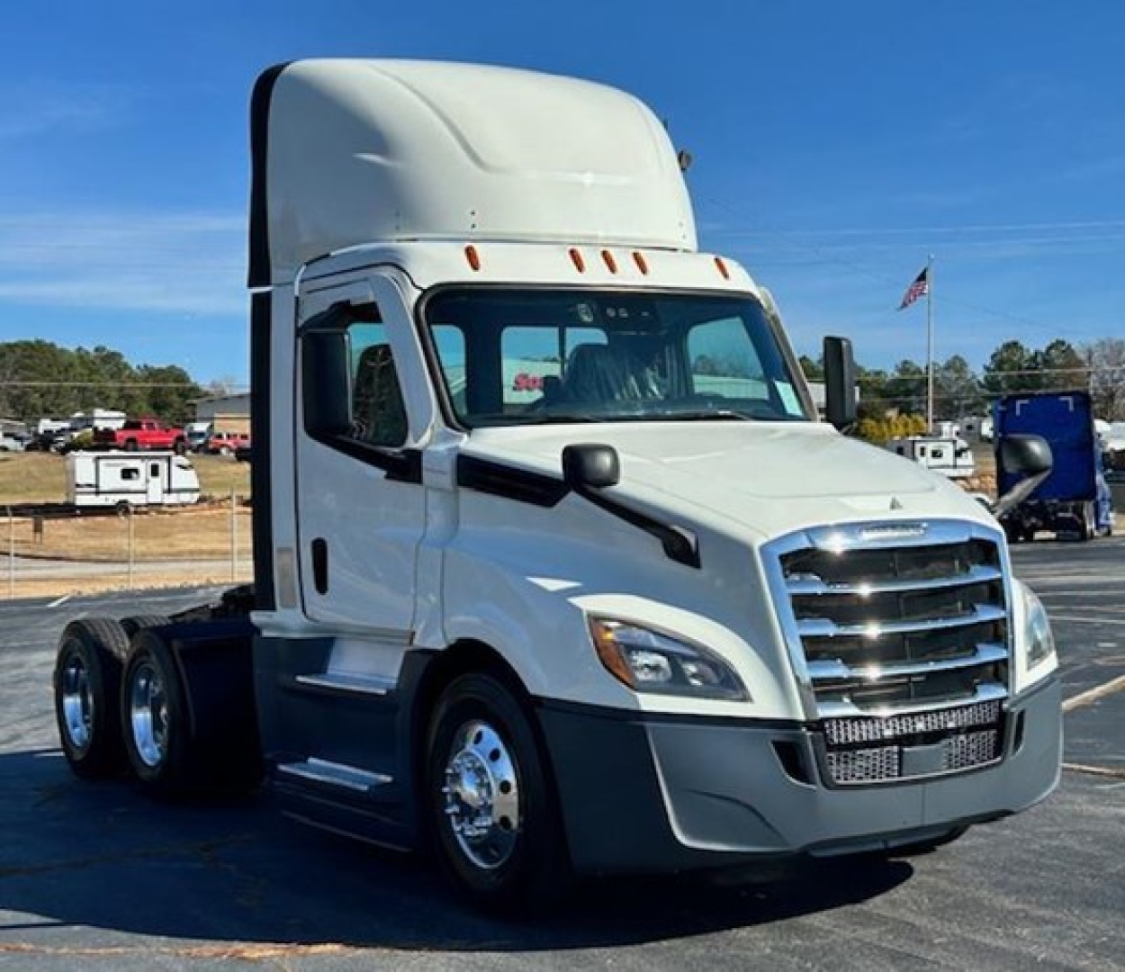 White Freightliner Cascadia 126 day cab truck front left view showing chrome grille, Headlights, side mirror, and stacked cab height, no visible text.