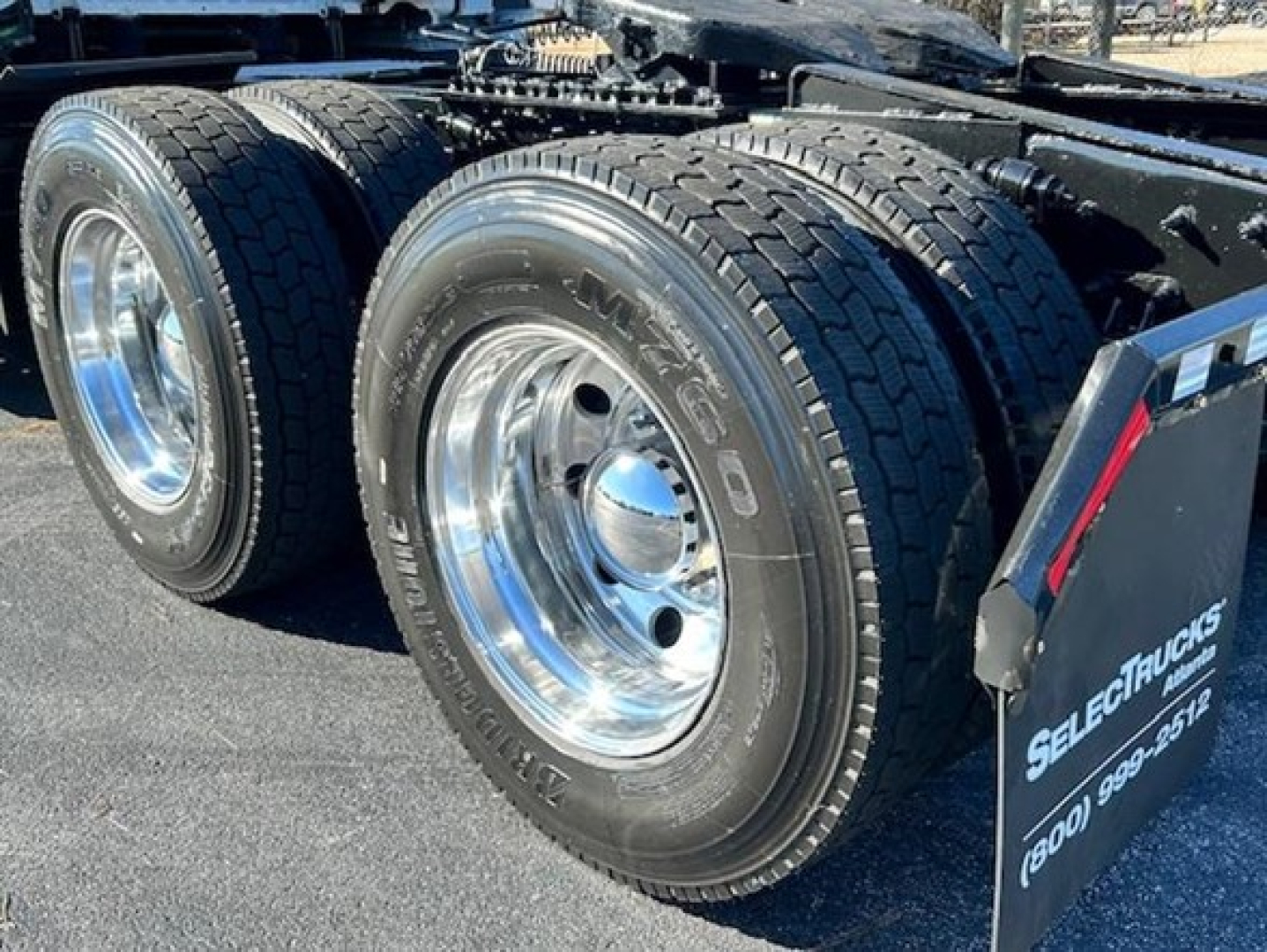 Freightliner Cascadia 126 truck rear dual tires and chrome wheel hubs showing on trailer chassis in service.