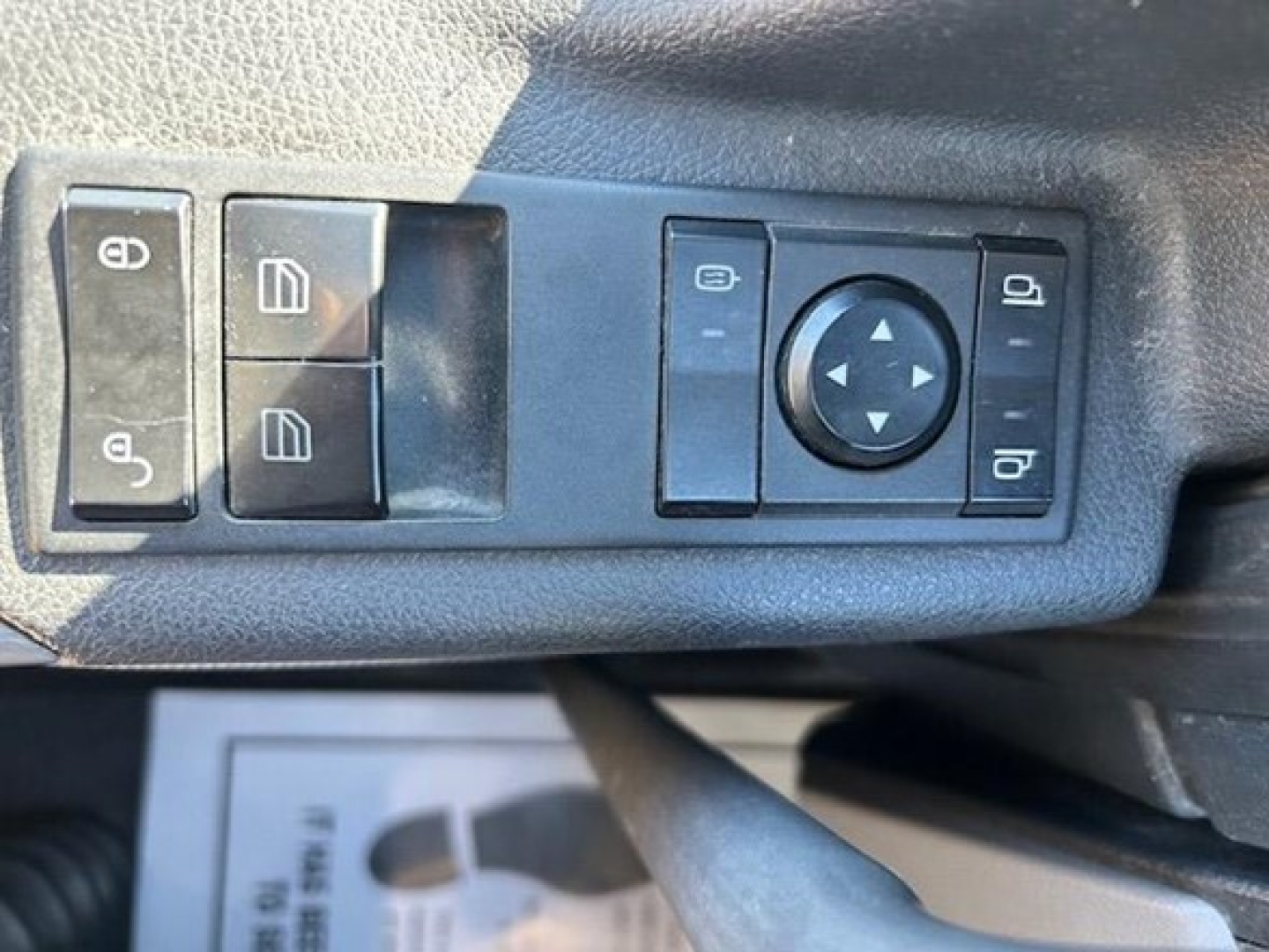 Operator controls on truck door panel with window/lock switches and a circular joystick-like control.