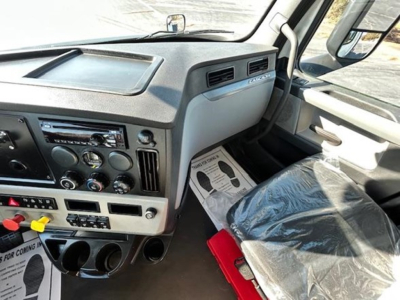 Cab interior of a 2021 Freightliner Cascadia 126 day cab showing dashboard controls, radio, climate dials, and cup holders.