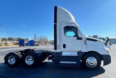 Freightliner Cascadia 126 day cab tractor side view showing chrome wheels and 3-axle configuration.