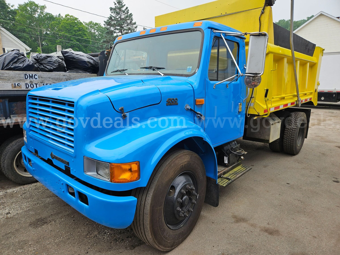 Truck dump bed: blue cab with yellow dump box, front grille, headlights, side mirror, and step; VIN and stock details not visible on image