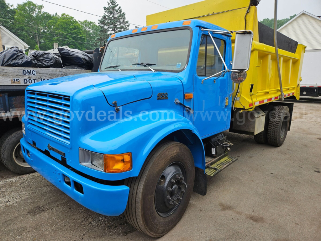 Truck dump bed: blue cab with yellow dump box, front grille, headlights, side mirror, and step; VIN and stock details not visible on image
