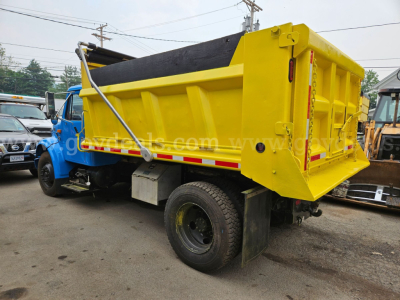 Dump truck with yellow dump bed and blue cab, side view showing tailgate and hydraulic lift on 1999 International 4700.