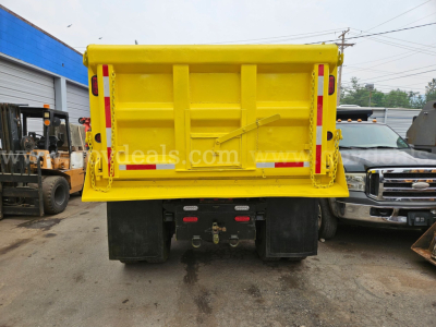  dump truck yellow dump bed rear view showing hydraulic tailgate and bumper with taillights and mud flaps.