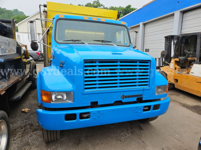 Blue 1999 International 4700 dump truck front view showing grille, headlights, bumper, and yellow dump bed.