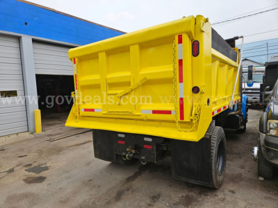 International 4700 dump truck rear view showing yellow dump bed and taillights.
