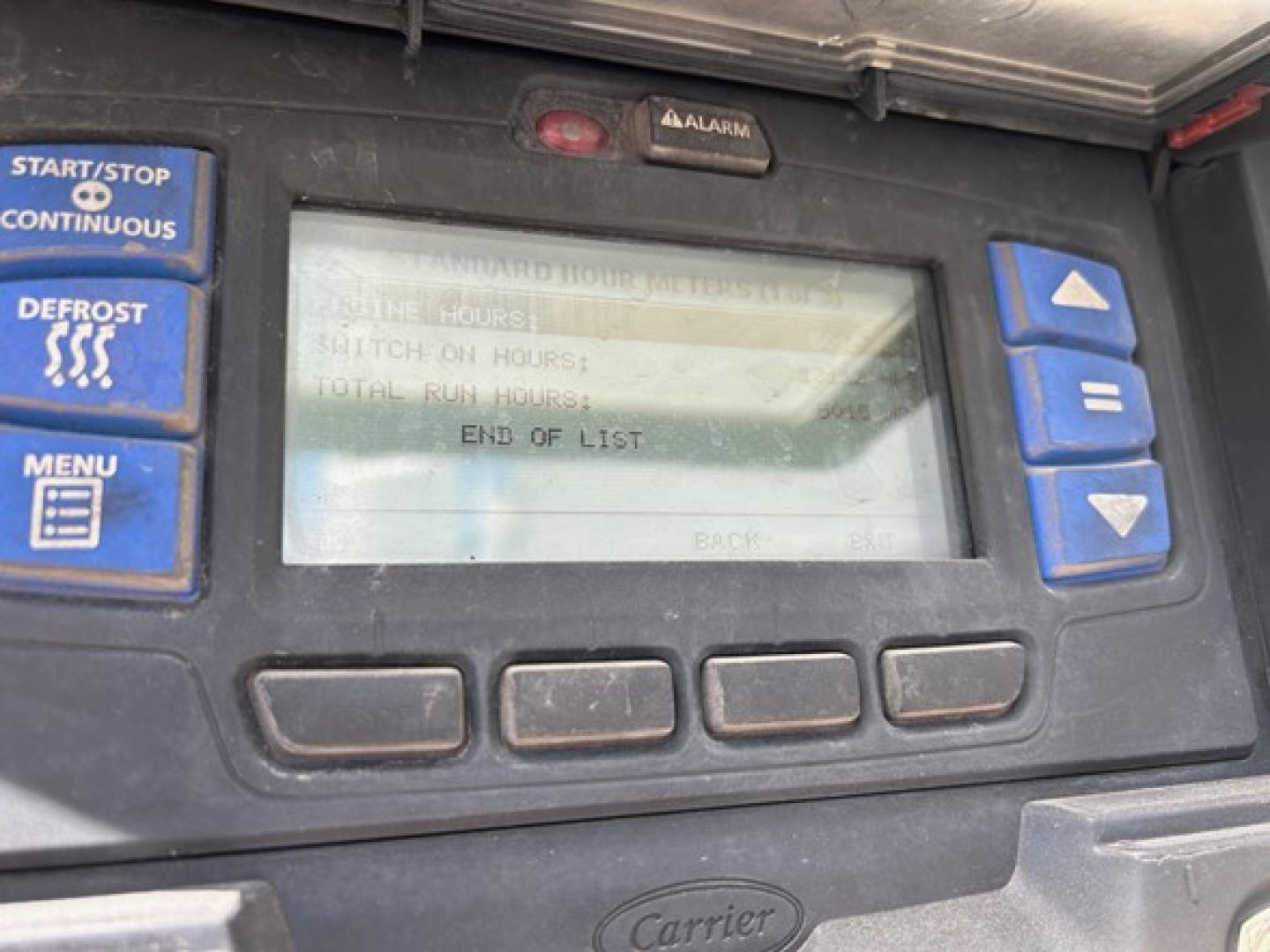 Trailer dashboard panel showing control buttons (Start/Stop, Defrost, Menu) and a central LCD screen with text; Carrier logo on lower panel area.