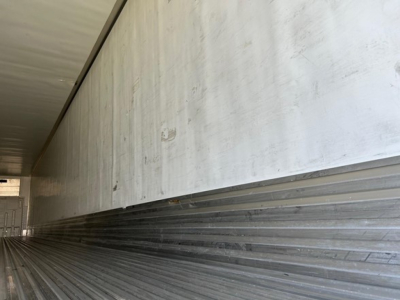 Rear interior of a utility trailer with aluminum side walls and ribbed floor; no visible text readable.