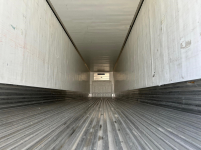Trailer interior showing empty refrigerated cargo area with ribbed floor and side walls, long perspective toward rear door.