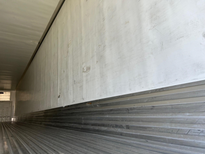 Trailer interior side wall and floor with ribbed metal flooring and smooth upper wall in a reefer trailer.