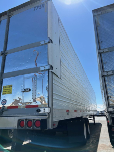 Rear and side view of a 2018 Utility 3000R trailer showing silver riveted metal walls, rear doors, taillights, and caution sticker.