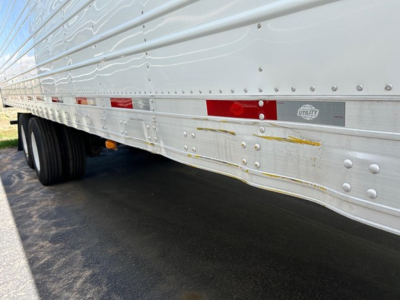 Utility 3000R trailer side view showing riveted aluminum siding with horizontal reflective tape and a small Utility logo plate.