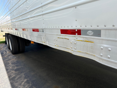 Trailer side view showing aluminum reefer trailer with reflective markers and Utility logo panel.