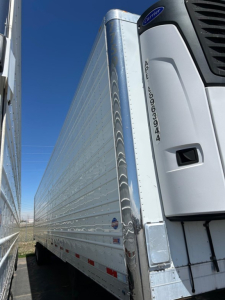 Reefer trailer side view showing Utility 3000R refrigeration unit with VIN APU numbers and corrugated aluminum side panels.