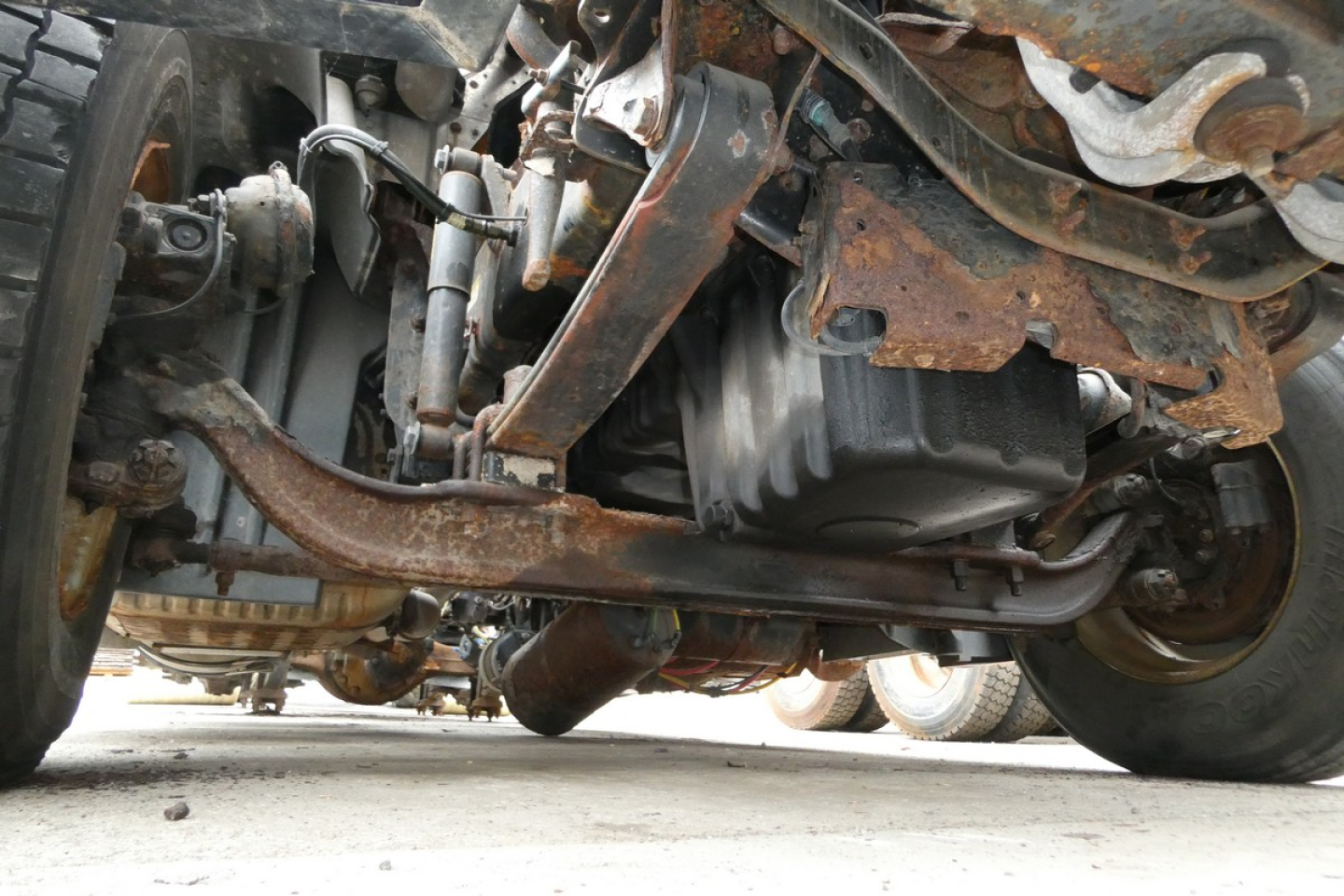 Underneath view of Freightliner Cascadia 125 front undercarriage showing suspension, drivetrain, and frame components.