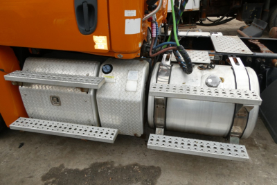 Truck fuel and tool boxes under the cab of a Freightliner Cascadia 125, with aluminum step plates, fuel tanks, and access panels visible.