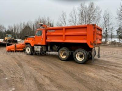 Dump truck side view showing an orange International 2574 dump truck with dual rear axles and a large dump bed.