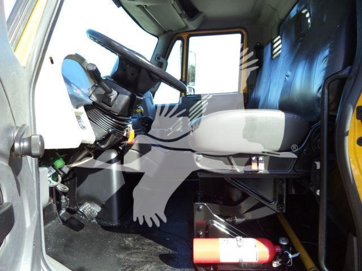 Cab interior of a 2019 International Durastar flatbed truck showing the steering wheel, driver's seat, and cabin with a fire extinguisher mounted under the dash.