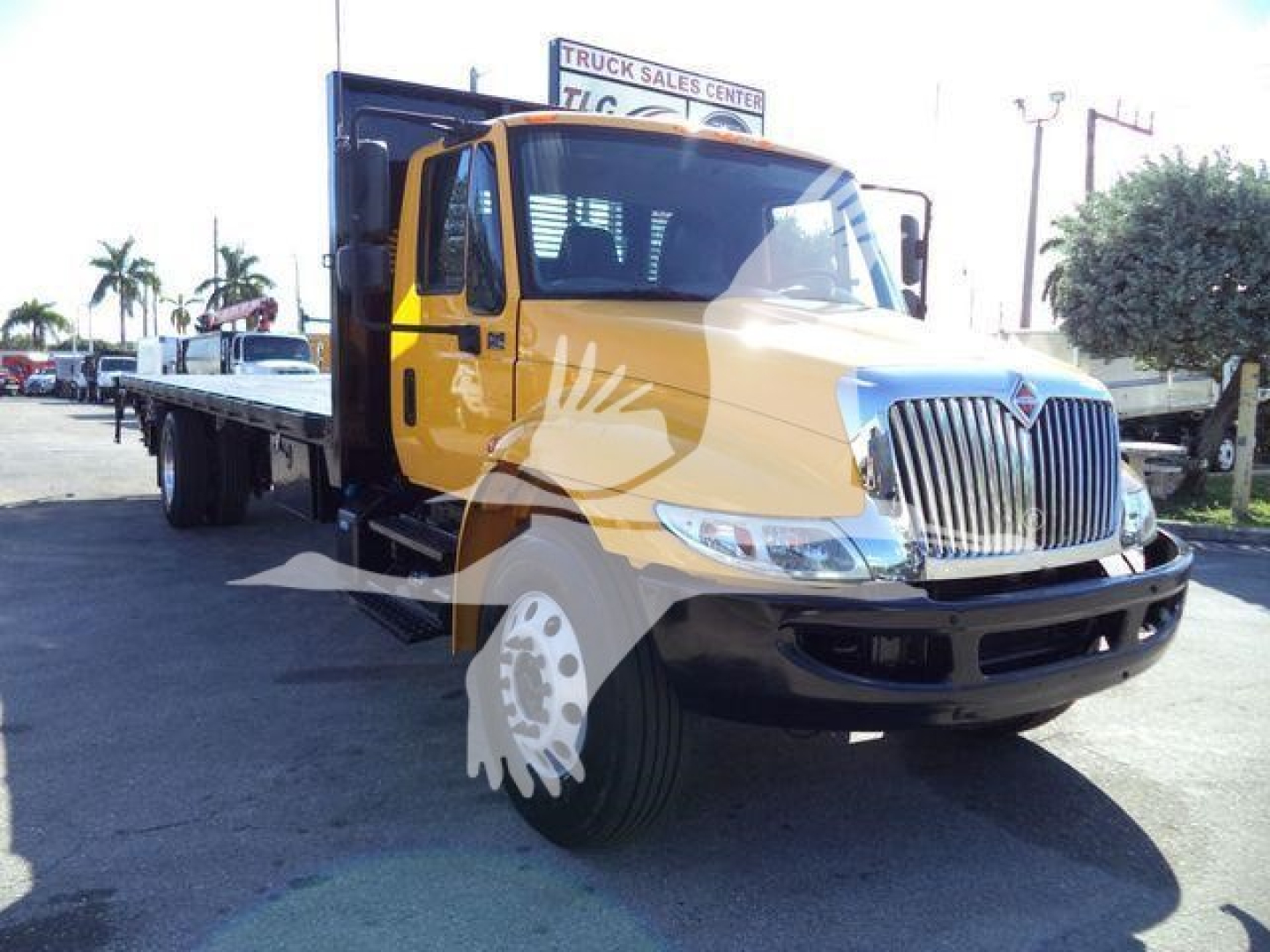2019 International Durastar flatbed truck from passenger side front angle showing yellow cab, chrome grille, black bumper, and flatbed cargo area.