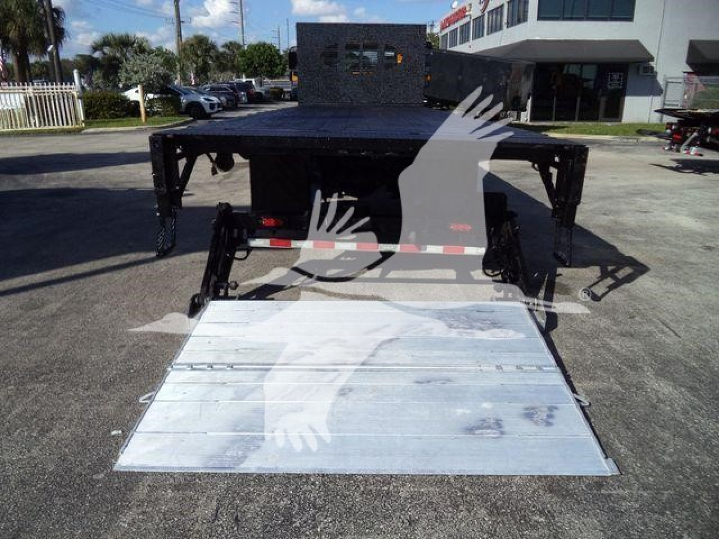 Flatbed tow truck chassis with lowered aluminum ramp and black metal frame, International Durastar trailer hitch area visible from rear.