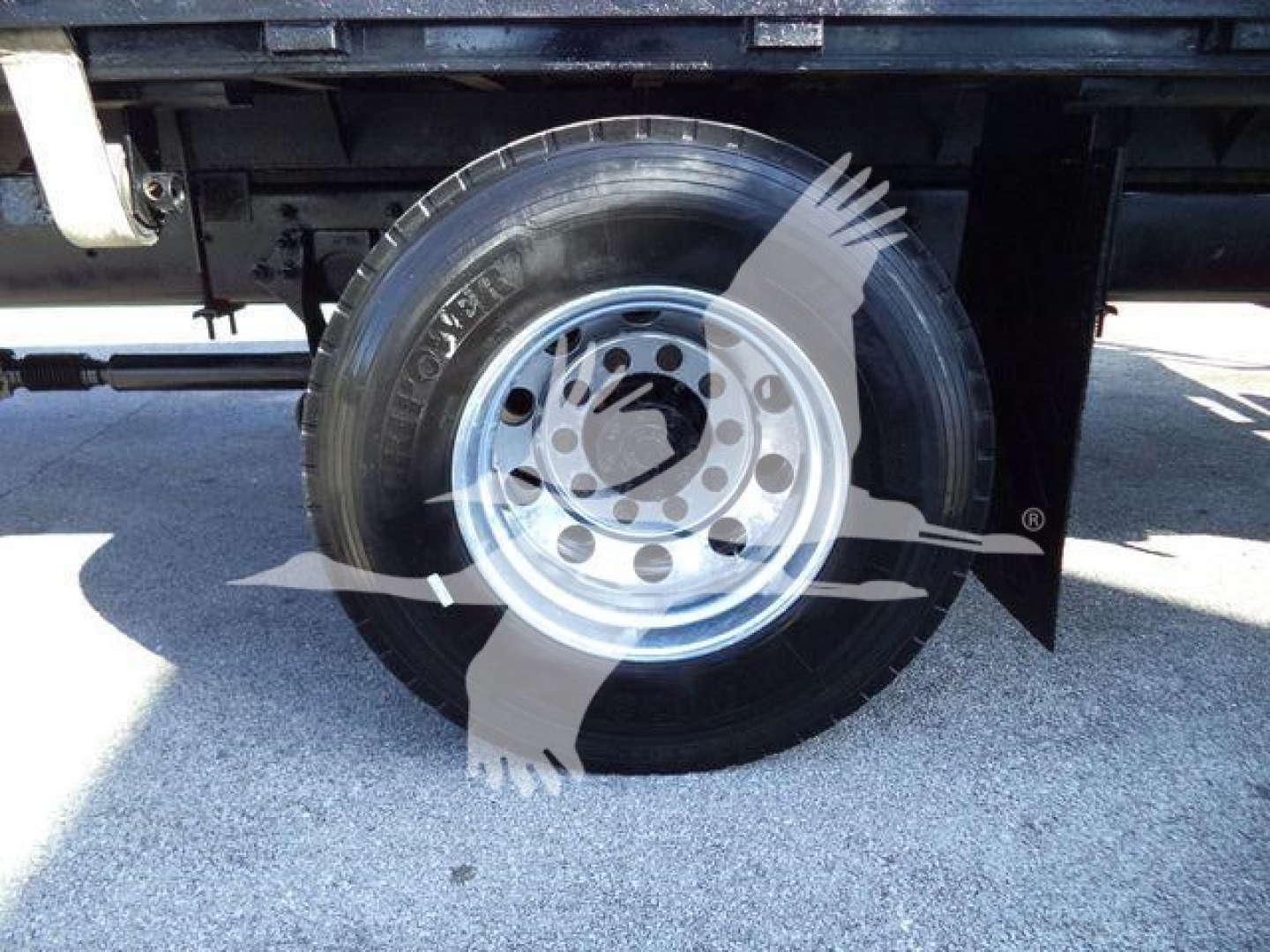 Wheel with tire marking showing Toyo? and rim under flatbed truck."