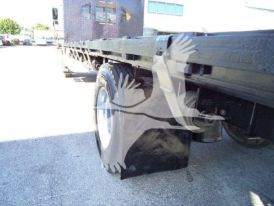 Flatbed truck rear wheel area of a 2019 International Durastar with dual rear wheels and dark mud flaps.