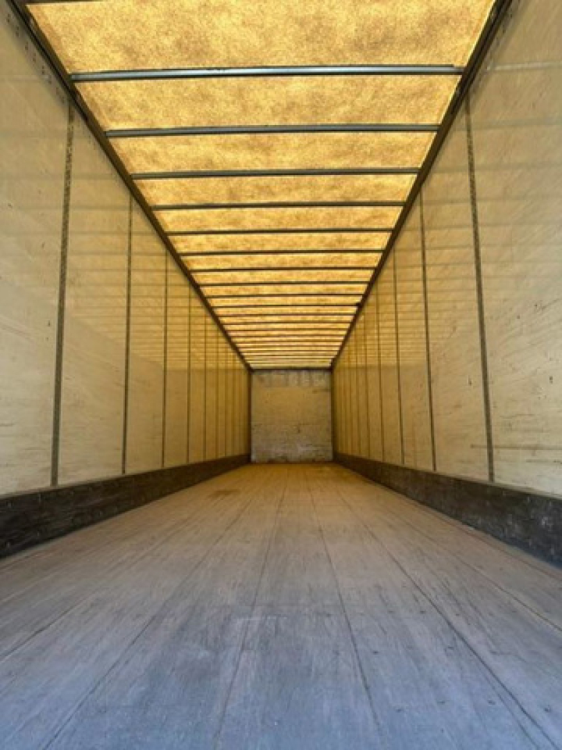 Trailer interior showing long empty cargo space with wooden roof panels and metal side walls.
